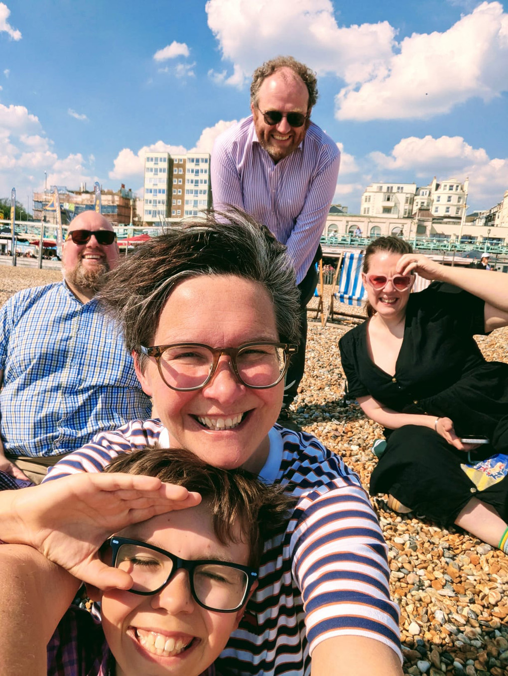 Five people on the beach, all wearing glasses