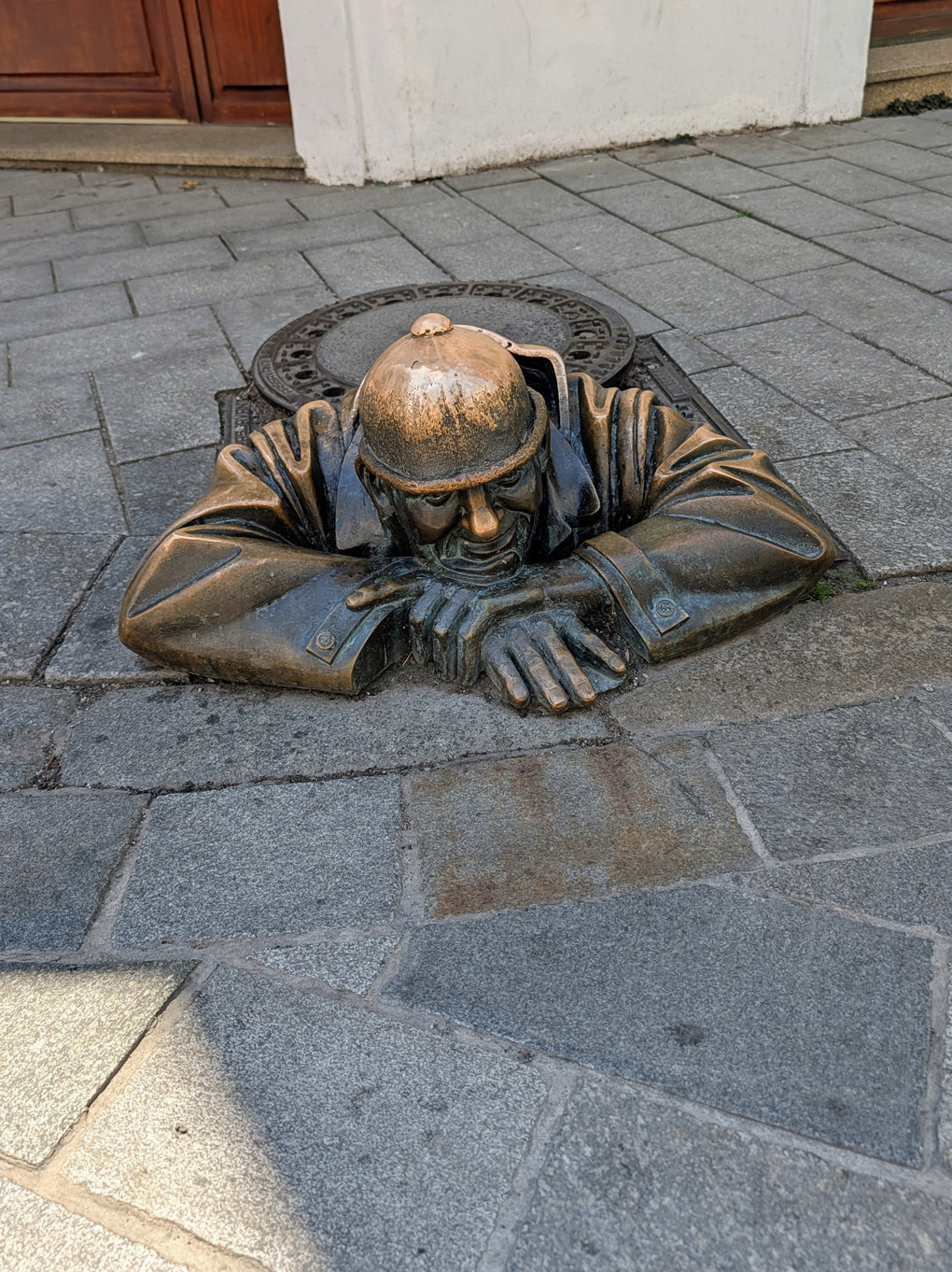 Bronze statue of a man crawling out of a man-hole in Bratislava.