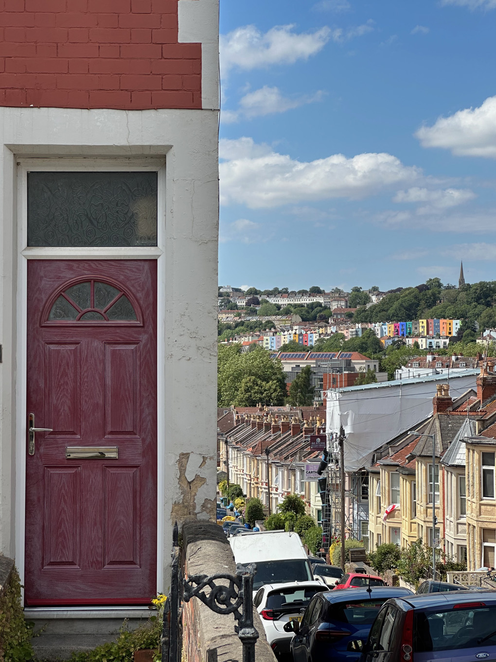 A house and front door and street undulating down and up into the distance with painted houses.