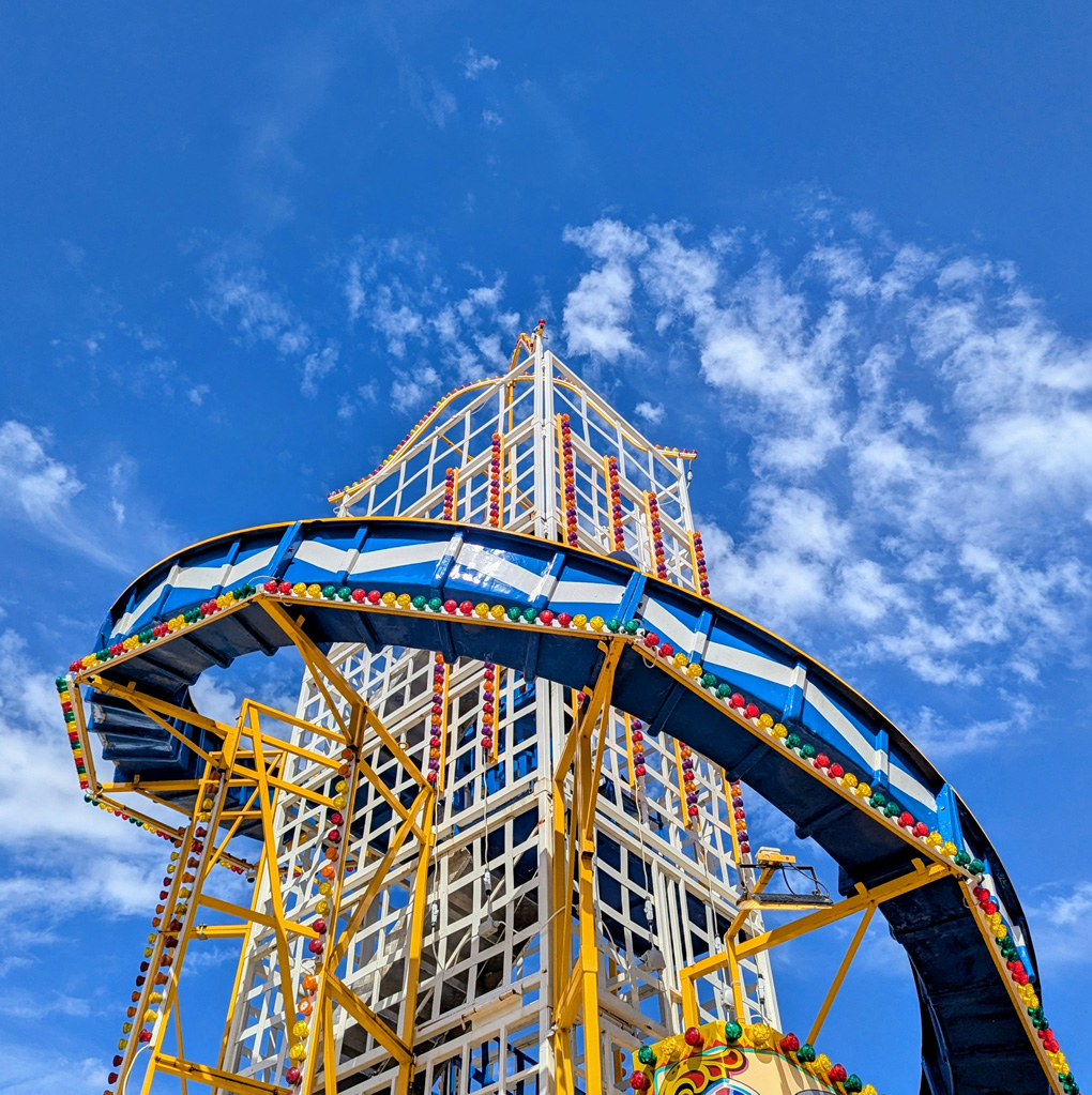 The top of a traditional helter skelter slide reaching into a bright sunny sky