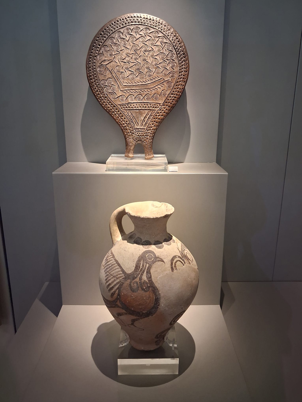 Ornate metallic frying pan, and a hand painted pottery urn.  The painting on the urn depicts a bird.