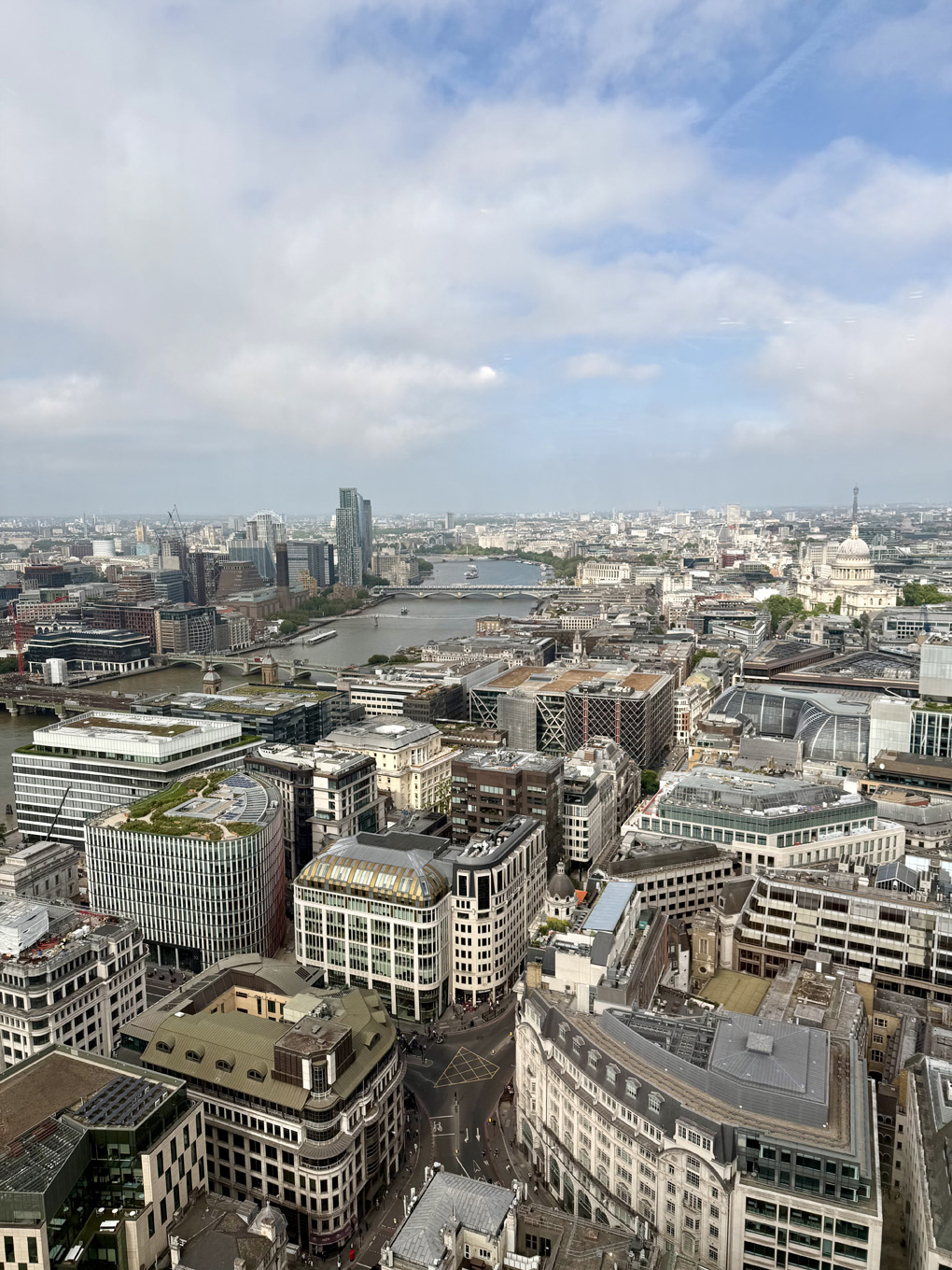 A high level view of London with the thames and St Pauls in the background. Blue sky and clouds above