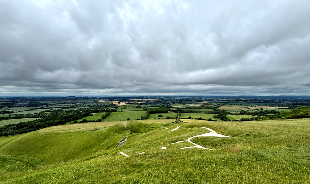 We're standing above the white horse carved into the chalk. There's a flattened hilltop further below, with a small area of chalk visible.