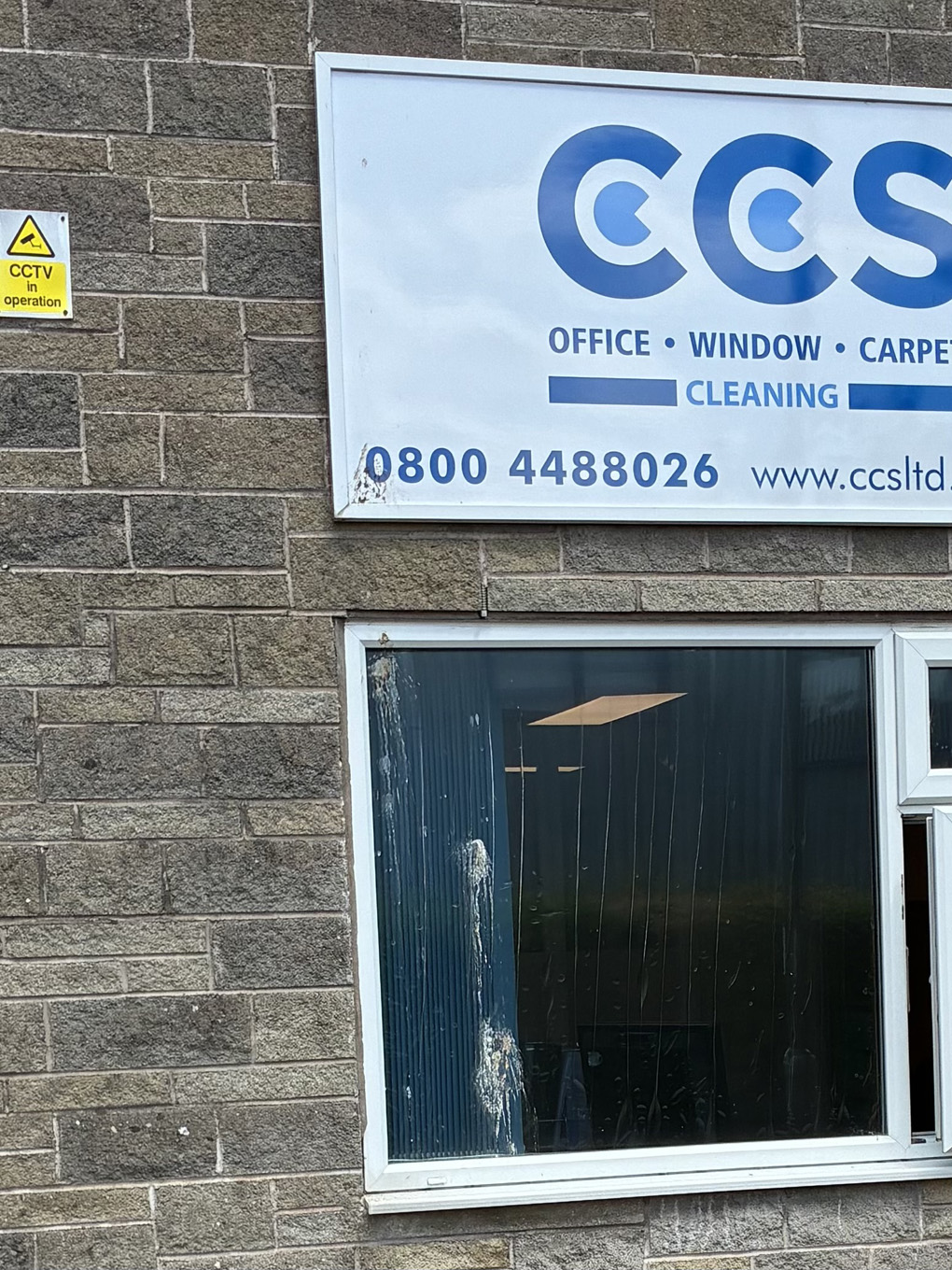A business sign advertising window cleaning set above a window which has a big smeary blob of bird poo dribbling down the entire length of the window.
