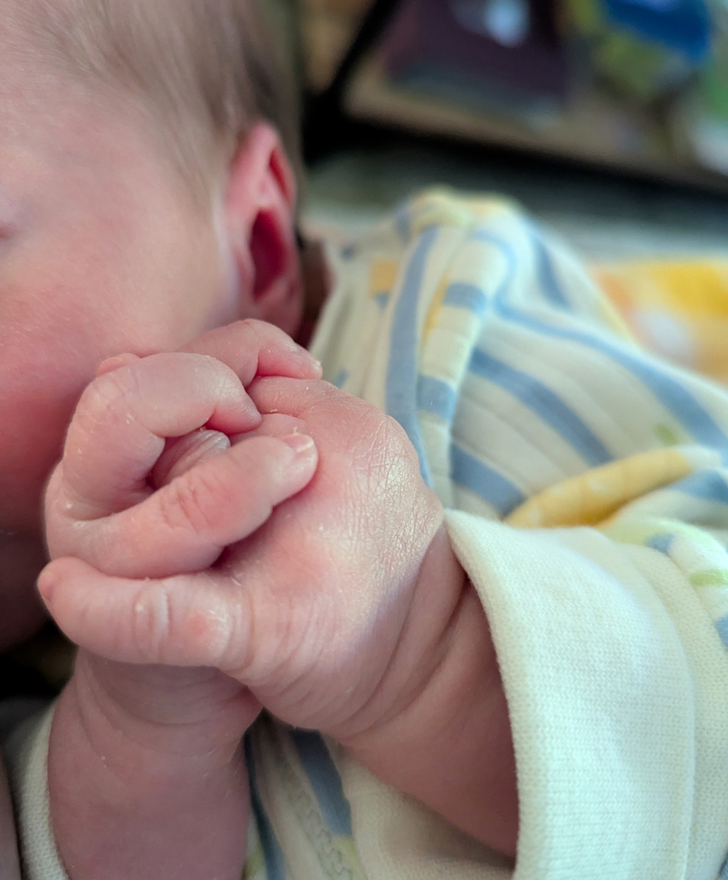 A close up of a tiny baby clasping their hands together.