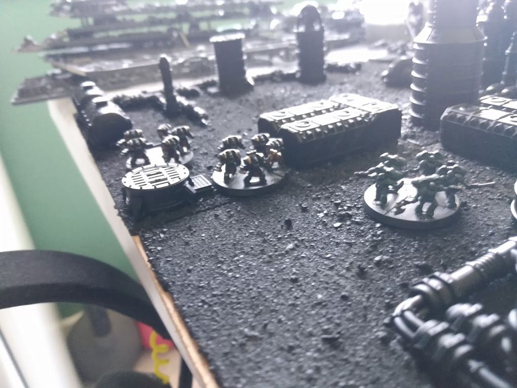 8mm scale miniatures stride across a tiny, unpainted battlefield