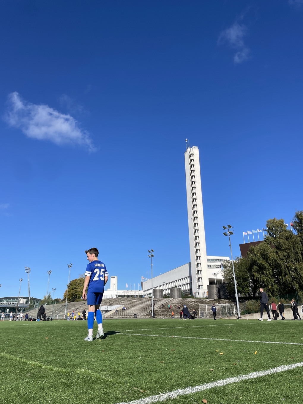 Boy in a football kit walking away from the camera.