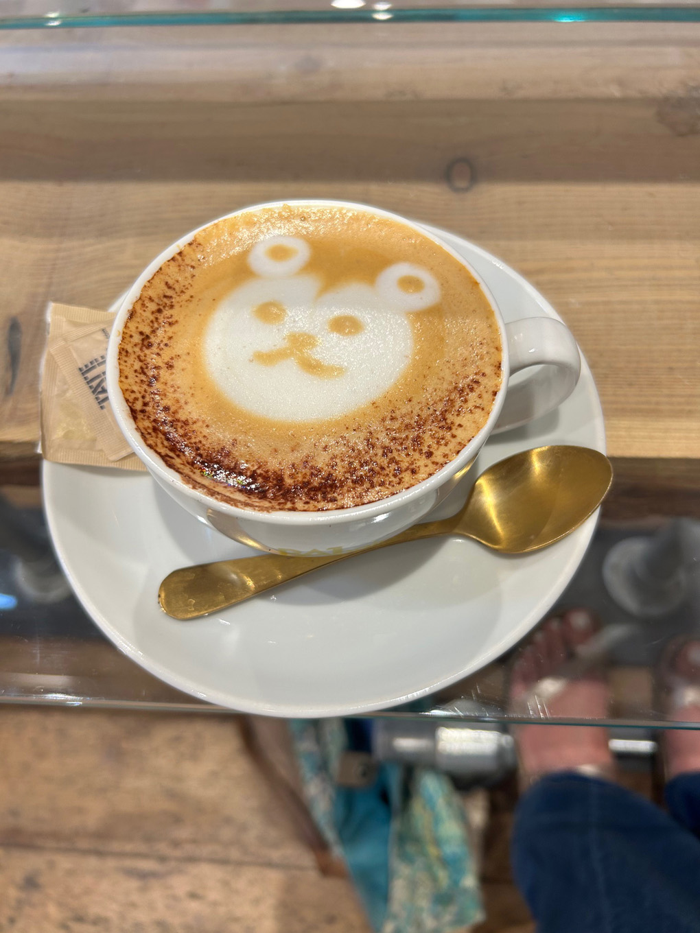 Picture of a milky coffee with the image of a cartoon bear fashioned out of the foam and froth on top of the mug.