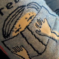 A pair of socks with the motif of a girl hiding behind a bok with the caption ' Fuck off I'm reading '