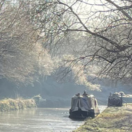 A cold looking canal with trees and a boat in the distance