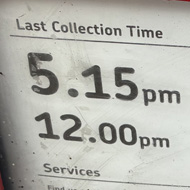 A red envelope with a kings head stamp, about to be placed in a red letter box