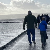 A scene of people walking on a path through the water.