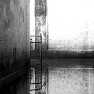 In this simple black and white image we view a subway from within, looking towards the exit. The subway is partially flooded and the still water reflects the walls and the barrier that prevents motor vehicles from entering.