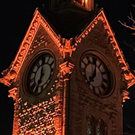 A clock tower, ominously lit in red. stranger things vibes.