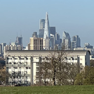 London skyline visible from Brockwell Park. Two people in distance sat on grass.