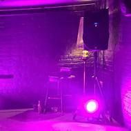 A tiny, garage sized venue with black walls and purple lighting.