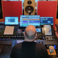 Stephen seated back to the camera in a mastering studio listening to the music.