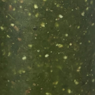 Three little bottles of green puréed food, on a shelf in a fridge.