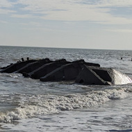 A wreck half exposed by the tide on the beach shore