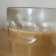 Tea inside a traditional one pint bear glass.sat on a wooden surface.