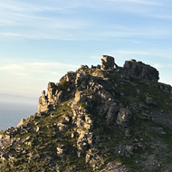 Rocks and hills with the sea behind them.