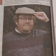 A newspaper opened on a double-page article headlined 