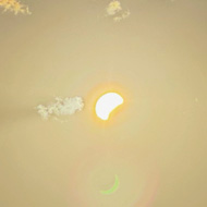 A partial occlusion of the late afternoon sun, with the shadow of the moon obscuring the lower-right portion of the sun