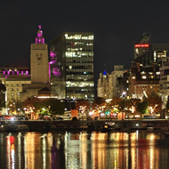 Distant illuminated buildings reflected in the dark waters of a dock, with the Liver Building in the centre.